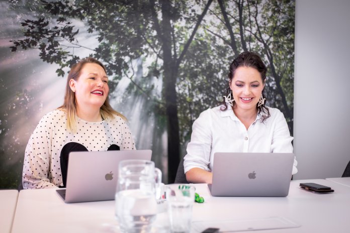 Kaksi henkilöä palaverissa hyväntuulisina