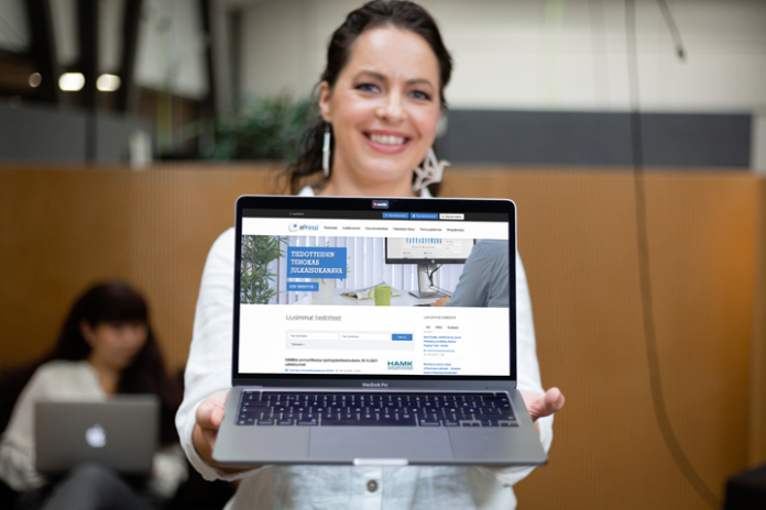 Henkilö pitelee tietokonetta, jonka näytöllä on ePressi-tiedotejakelupalvelun käyttöliittymä