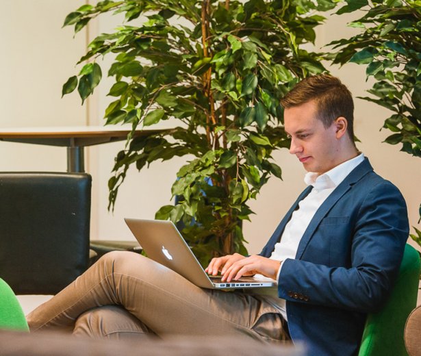 Hymyilevä mies käyttämässä tietokonetta