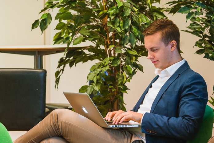 Hymyilevä mies käyttämässä tietokonetta